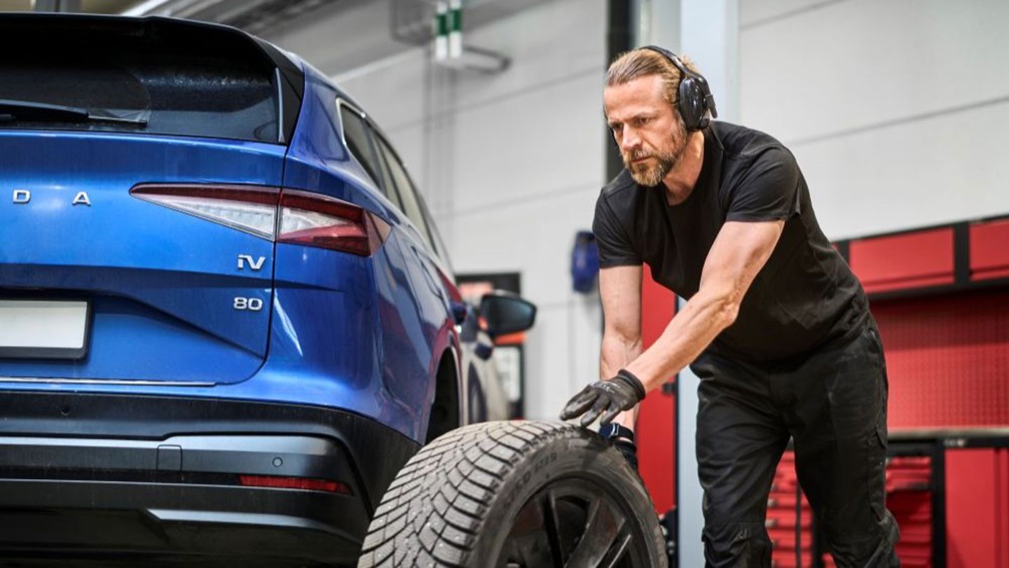 Bildet viser en mann og ei dame som står utenfor et bilverksted. 