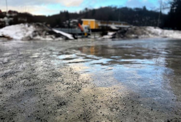 Bildet viser en islagt bakke som delvis er strødd med strøsand. 