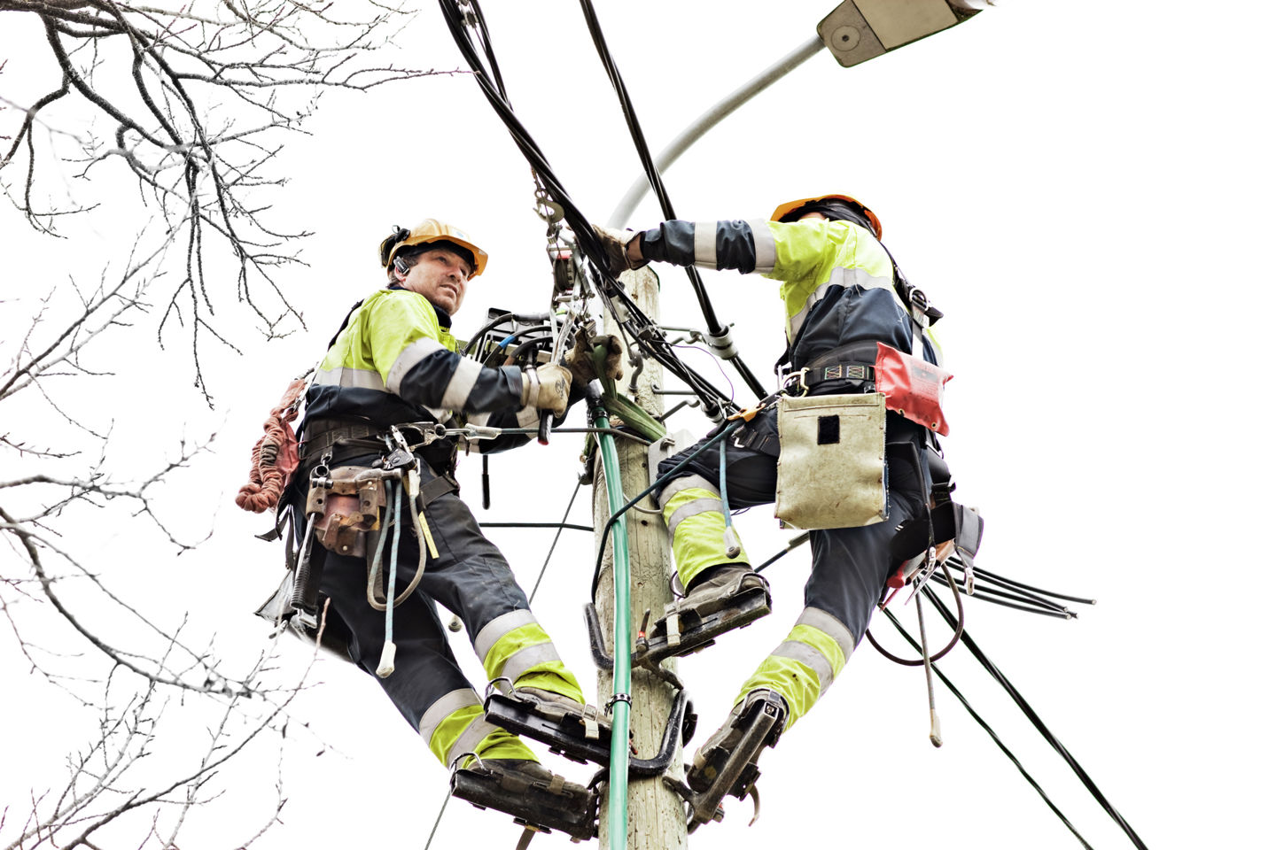 Bildet viser to personer som jobber oppe i ei høyspentmast. 