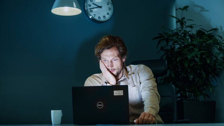 en mann sitter ved kontorpulten med pc sent på kvelden