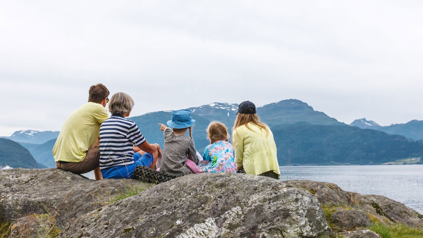 Bildet viser en familie som ser ut mot fjell og fjord.
